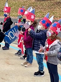 students standing outside holding flags and wearing patriotic hats