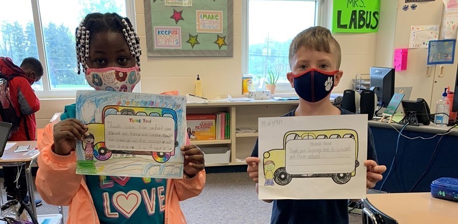 students holding thank you notes to bus drivers