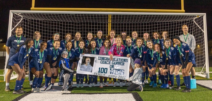 girls soccer players and coach celebrating 100th win