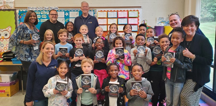 students, teacher principal and Rotary Club members holding dictionaries