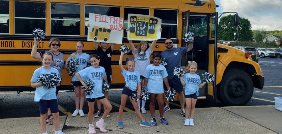 students and staff standing outside of a school bus
