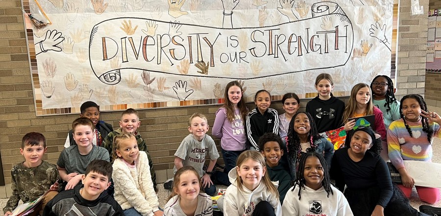 students sitting in front of bulletin board reading diversity is our strength
